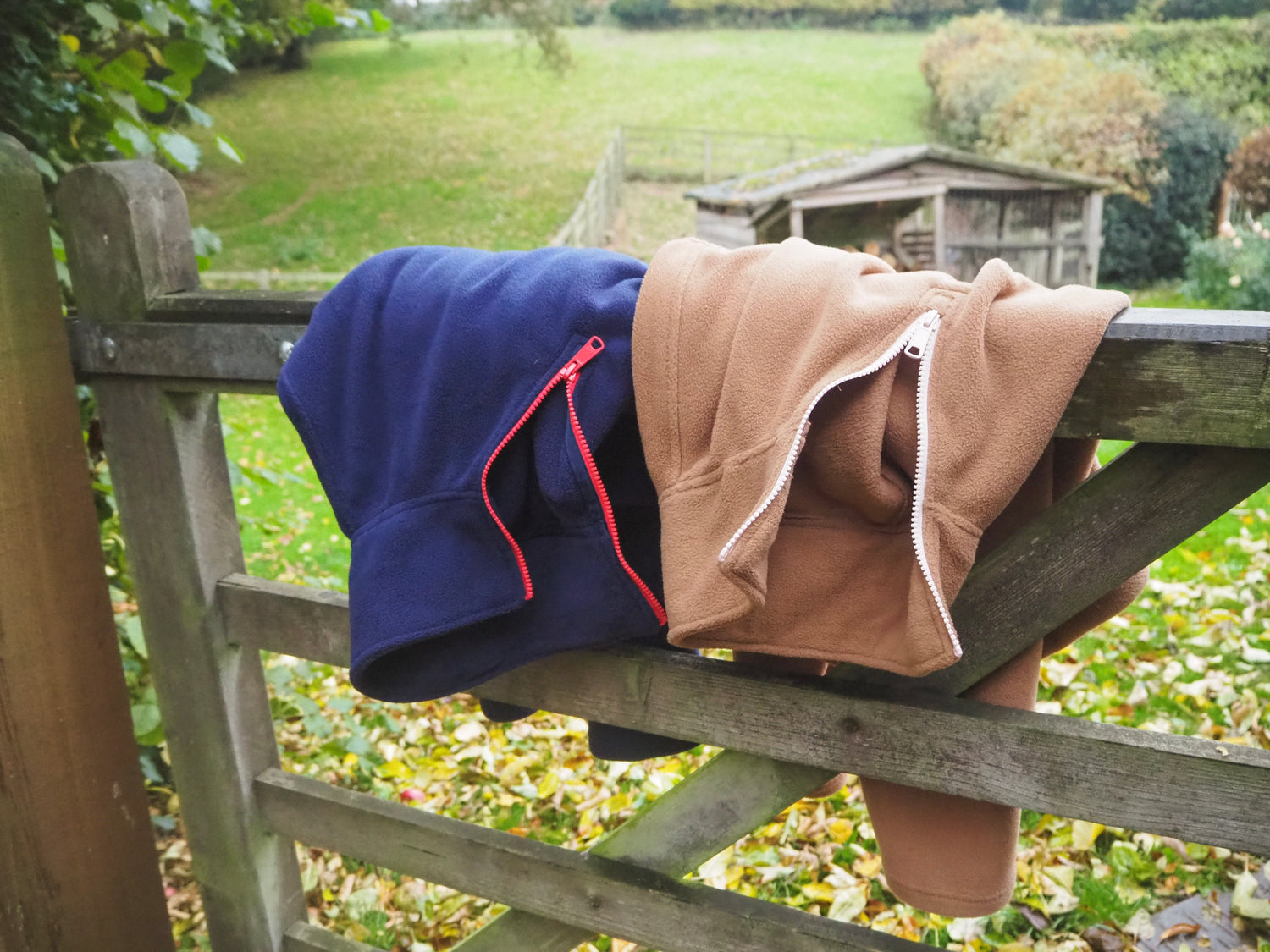 The Nantucket and Jaipur fleeces draped over a wooden fence in the countryside.