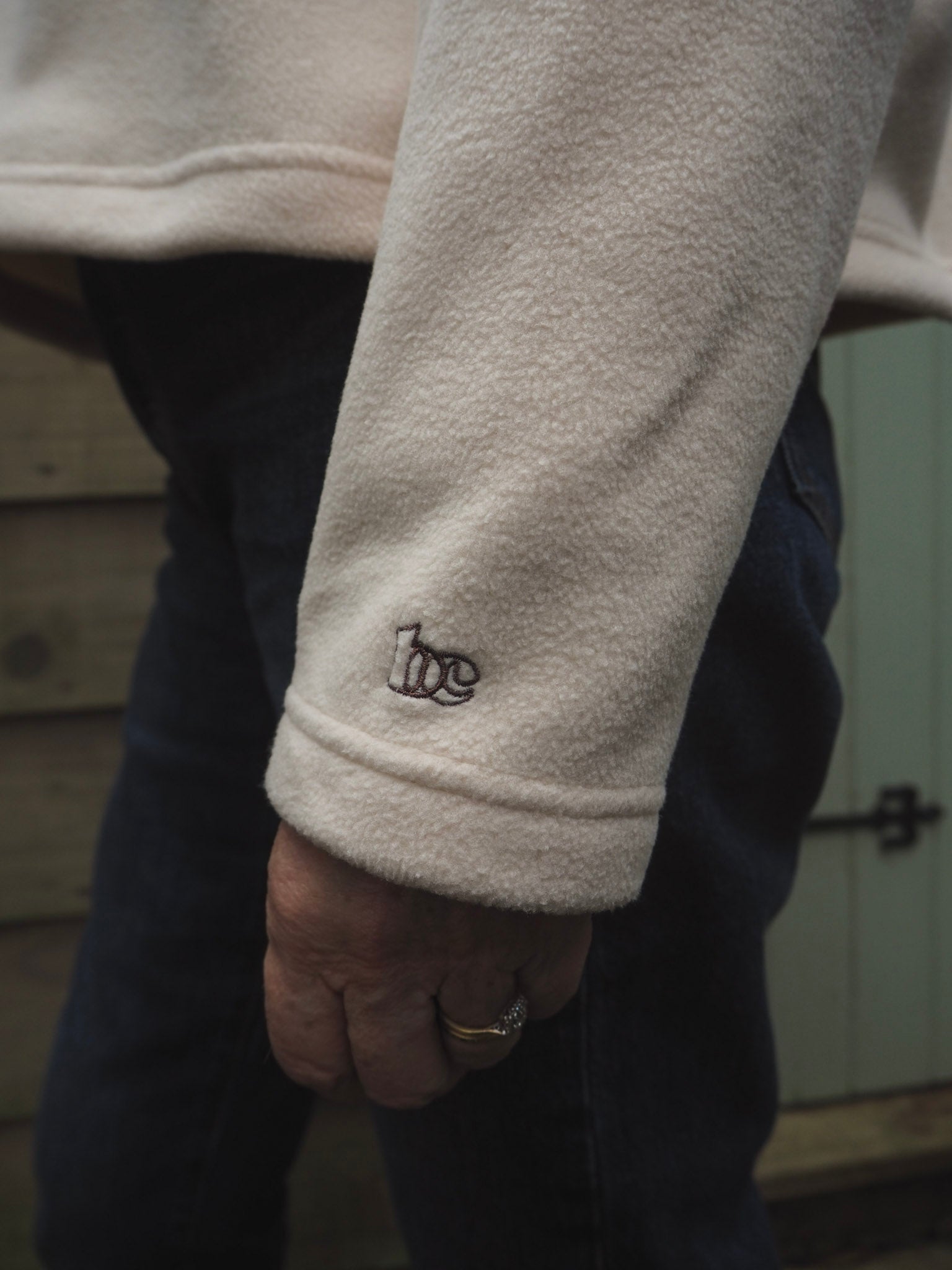 Close-up of Sallie wearing the Courchevel cream fleece with the BC logo on the cuff. 