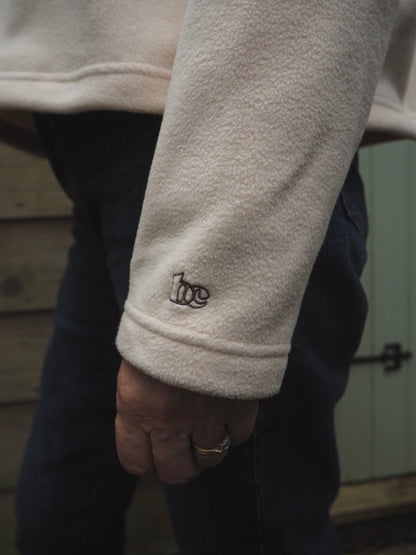 Close-up of Sallie wearing the Courchevel cream fleece with the BC logo on the cuff. 