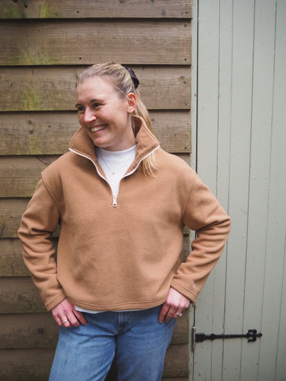 Our model Maddi wearing The Jaipur camel fleece pullover standing outside in the countryside. 