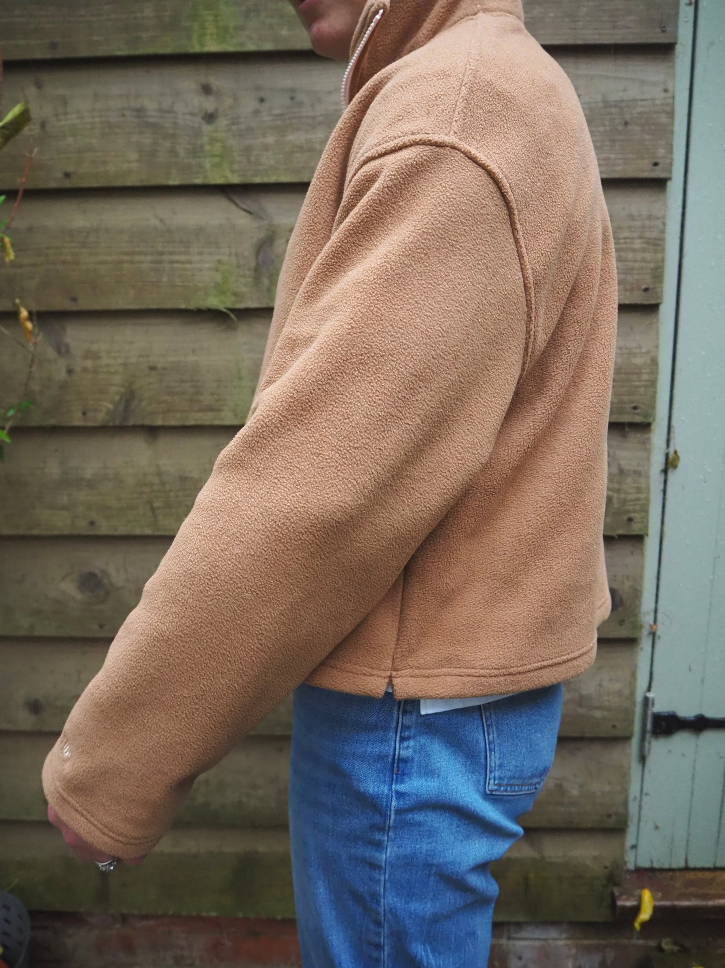 Our model Maddi wearing The Jaipur camel fleece 1/4 zip standing outside in the countryside. 