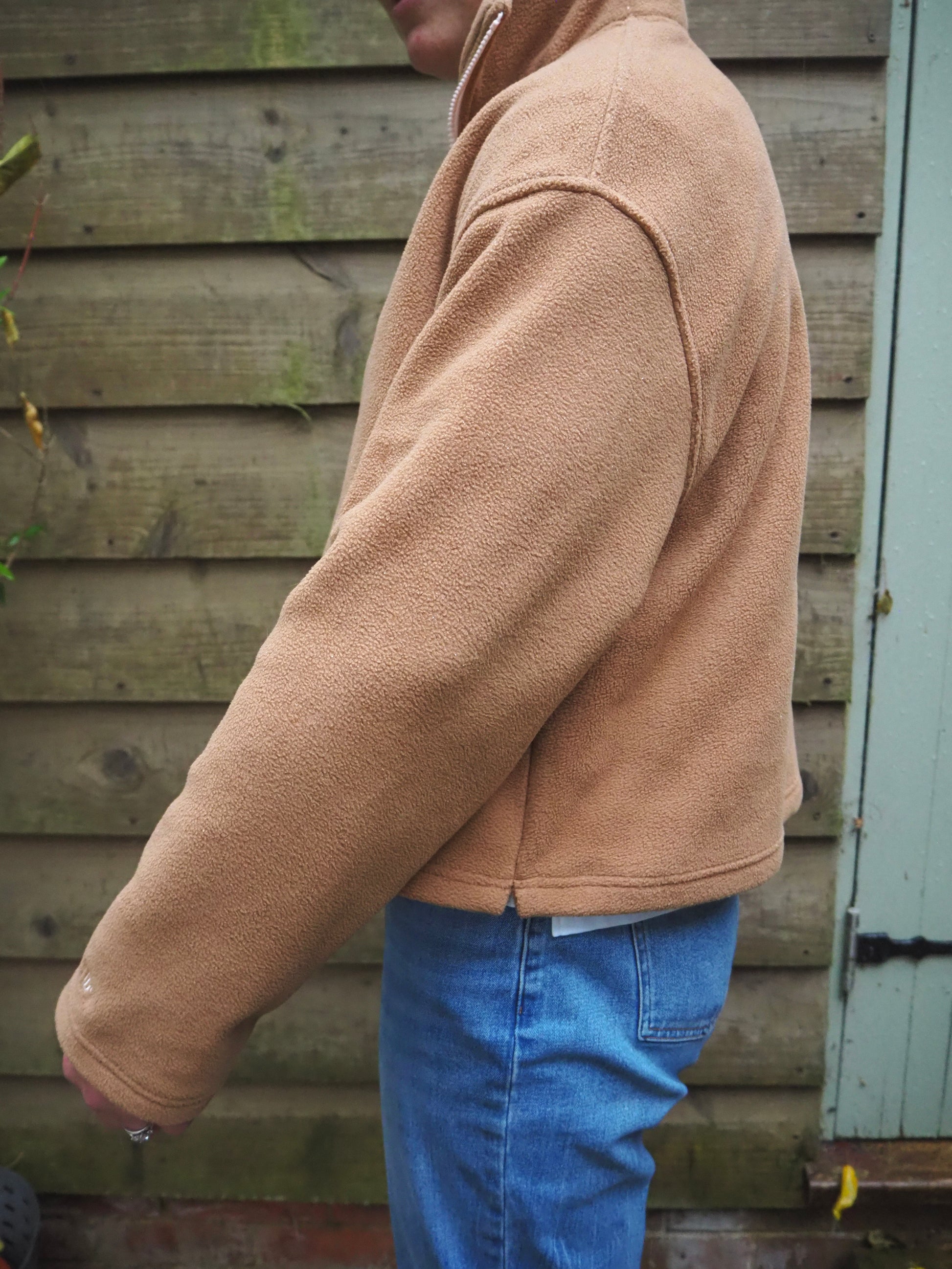 Our model Maddi wearing The Jaipur camel fleece 1/4 zip standing outside in the countryside. 