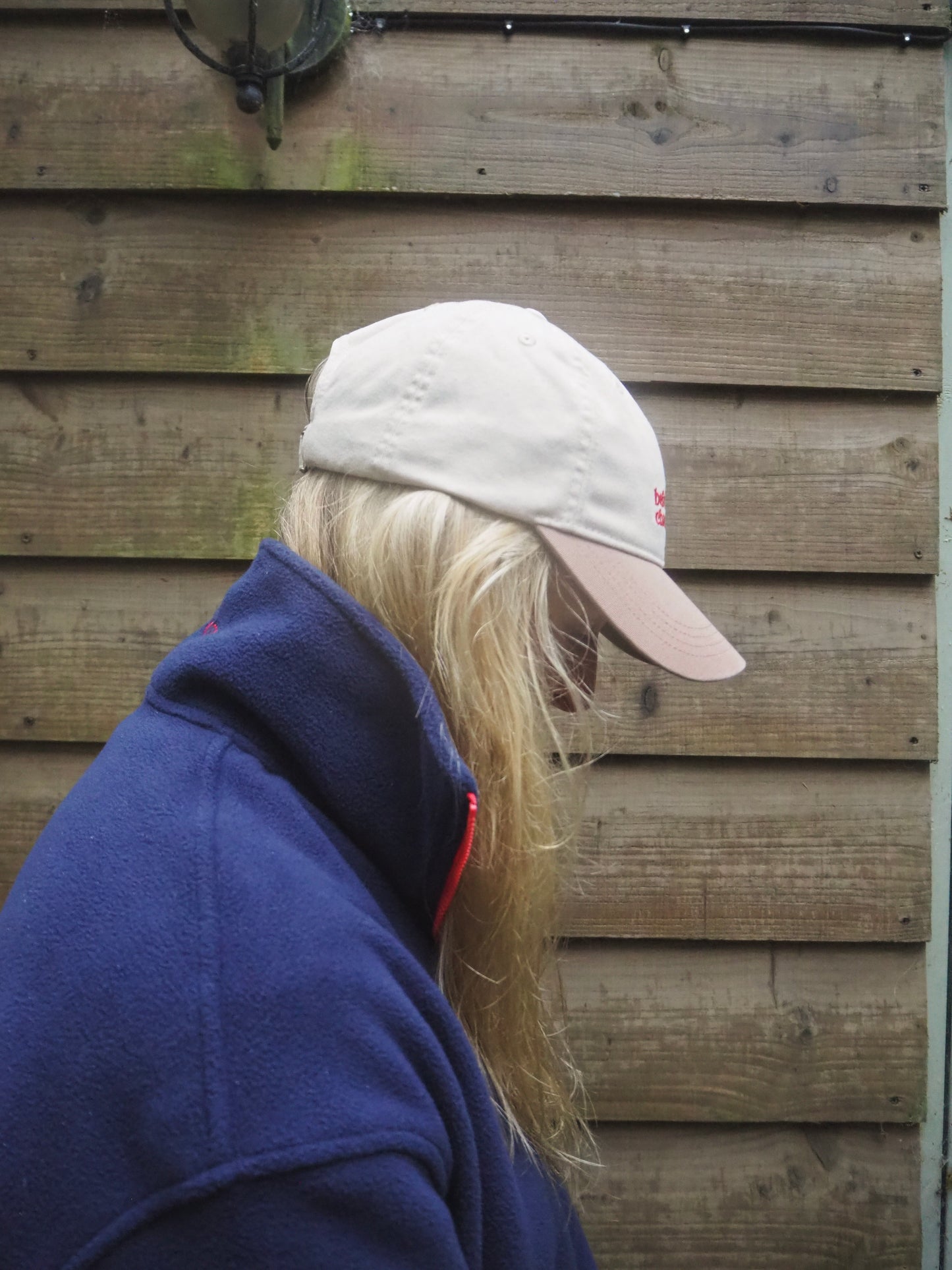 Maddi is wearing a two-tone beige cap and navy blue fleece