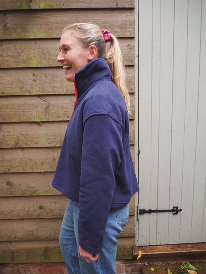 Maddi is wearing the Nantucket navy blue fleece 1/4 zip, standing in the countryside. 