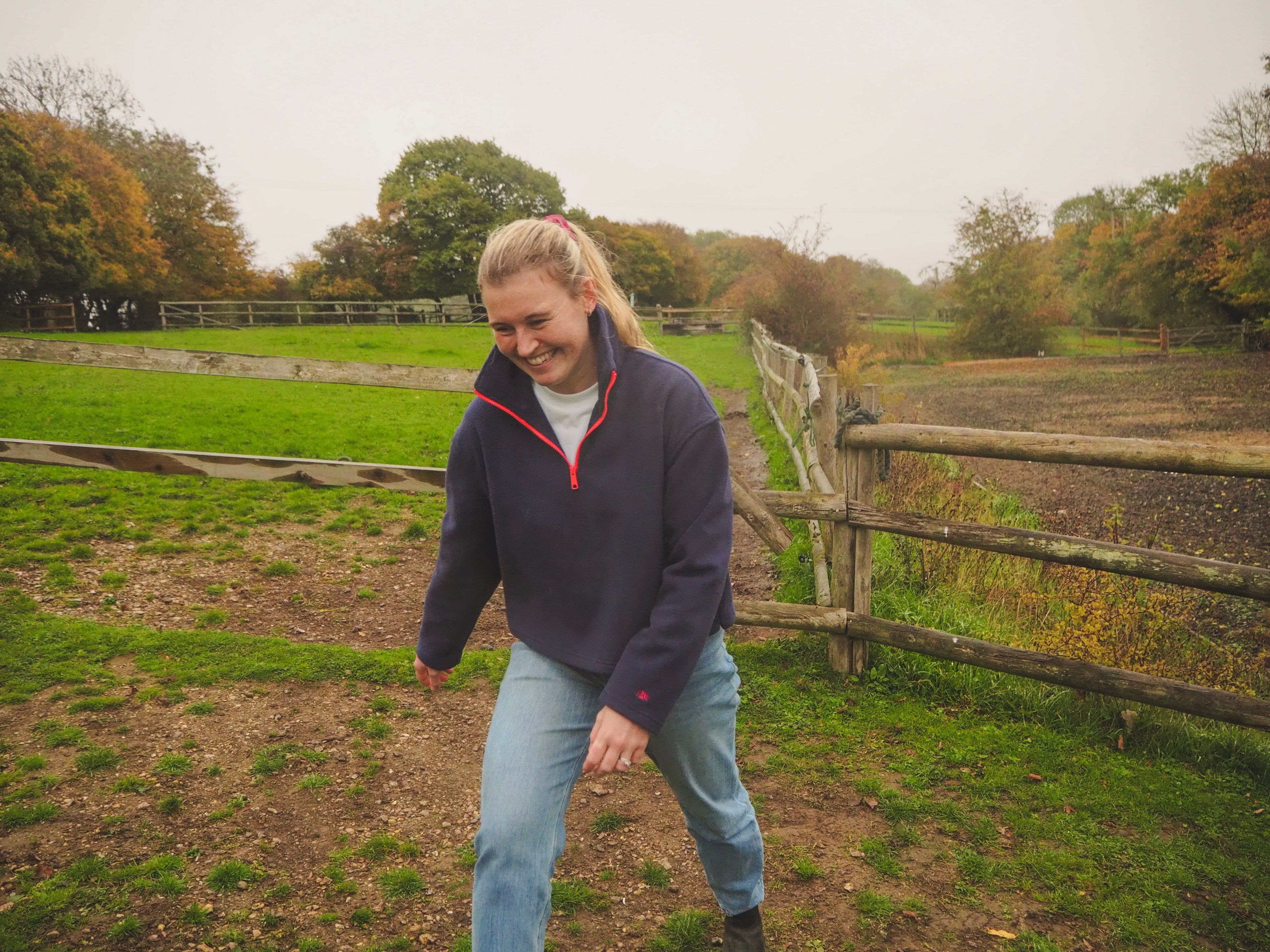Maddi standing in a field wearing a Before Charlotte navy blue and red fleece